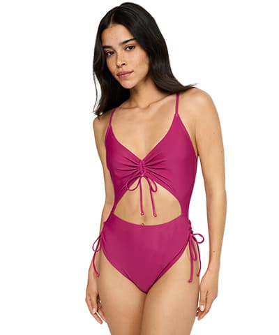 Frau in pinkem Badeanzug mit Cut-Outs und Schnürdetails an Taille und Brust, steht vor weißem Hintergrund