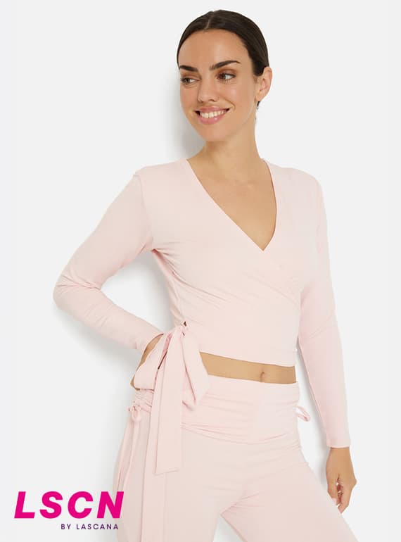 LSCN by Lascana – Frau in hellrosa Wickel-Longsleeve und passender Hose blickt lächelnd zur Seite