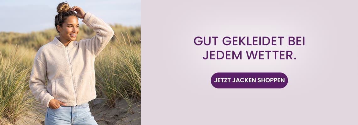 Gut gekleidet bei jedem Wetter – Frau im Sand mit heller Jacke, eine Hand im Haar, daneben Button „Jetzt Jacken shoppen“