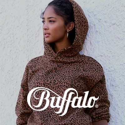 Buffalo – Frau trägt braunen Hoodie mit Leopardenmuster vor weißer Wand