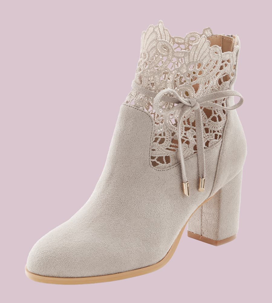 Eleganter grauer Stiefelette mit Spitze und Schnürung, Absatz und floralem Muster auf rosa Hintergrund.