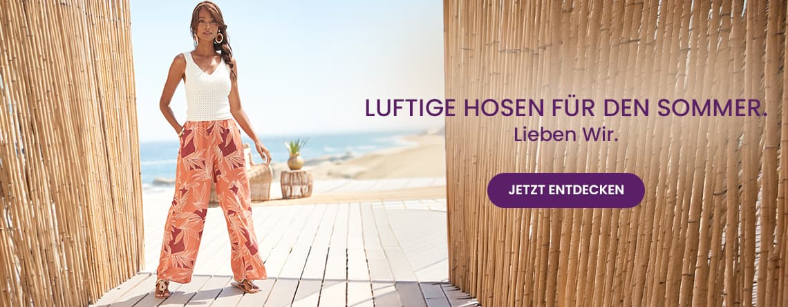 LUFTIGE HOSEN FÜR DEN SOMMER – JETZT ENTDECKEN – Person in weiter gemusterter Hose steht auf Holzsteg am Strand