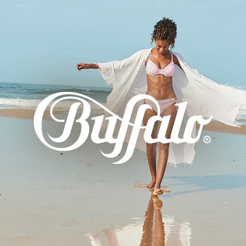Buffalo Logo vor Frau im Bikini mit offenem Strandkimono, die barfuß am Meeresufer entlangläuft