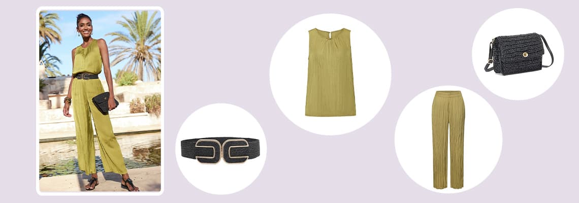 Frau im olivgrünen Jumpsuit mit schwarzem Gürtel, passender Hose, Top, Clutch und Umhängetasche vor Palmen