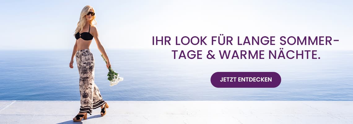 Ihr Look für lange Sommertage & warme Nächte – Frau im Bikini-Top und langem Rock geht mit Blumen am Meer entlang