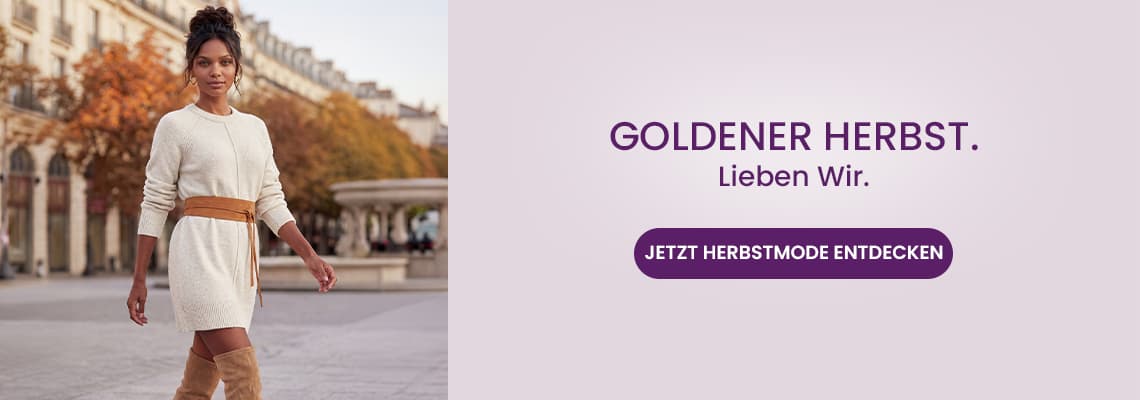 GOLDENER HERBST. Lieben Wir. – Frau im hellen Strickkleid und Stiefeln spaziert vor herbstlichen Bäumen in der Stadt